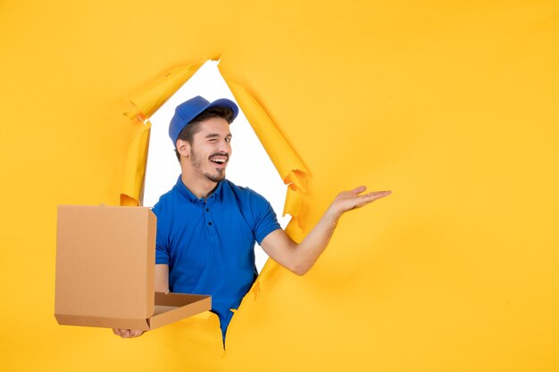 Vue de face du courrier masculin tenant une boîte à pizza ouverte sur un espace jaune