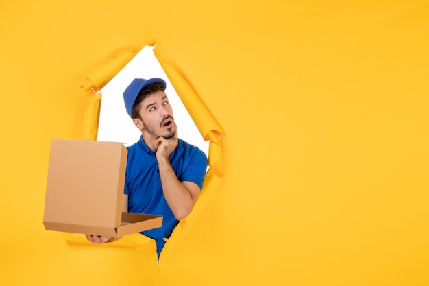 Photo gratuite vue de face du courrier masculin tenant une boîte à pizza ouverte sur un espace jaune