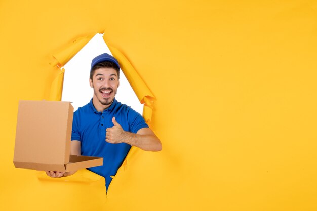 Vue de face du courrier masculin tenant une boîte à pizza ouverte sur un espace jaune