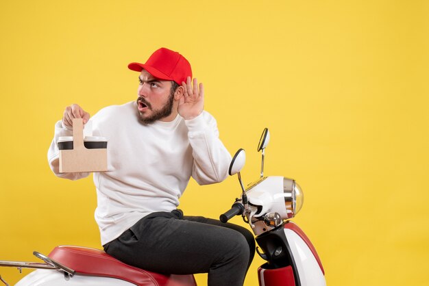 Vue de face du courrier masculin tenant le café de livraison sur le mur jaune