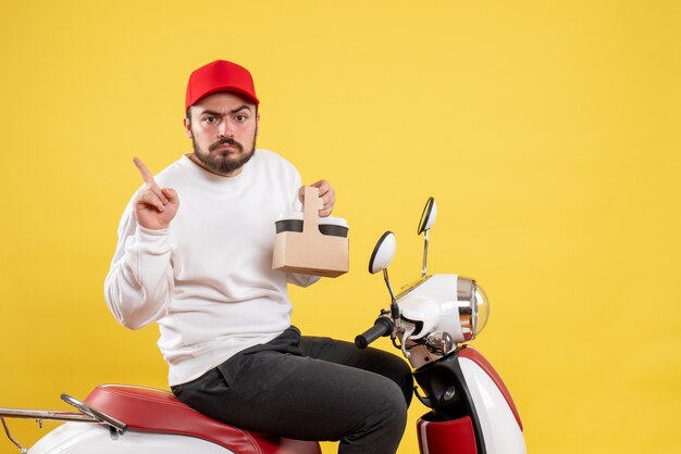 Vue de face du courrier masculin tenant le café de livraison sur le mur jaune