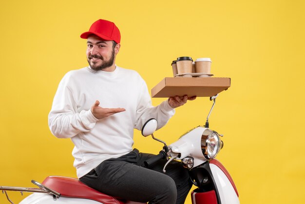 Vue de face du courrier masculin tenant le café et la nourriture de livraison sur le mur jaune