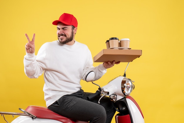 Vue de face du courrier masculin tenant le café et la nourriture de livraison sur le mur jaune