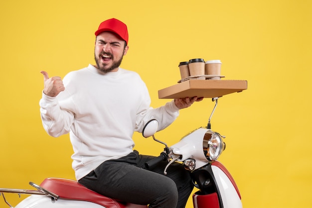 Vue de face du courrier masculin tenant le café et la nourriture de livraison sur le mur jaune