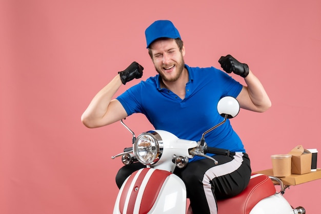 Vue de face du courrier masculin en uniforme bleu et des gants sur la couleur rose travail de restauration rapide service de vélo livraison de nourriture