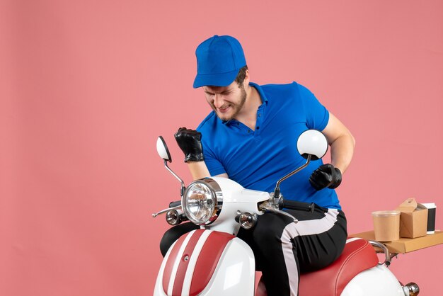 Vue de face du courrier masculin en uniforme bleu et des gants se réjouissant de la couleur rose travail de restauration rapide service de vélo livraison de travail alimentaire