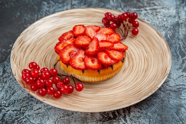 Vue de face du délicieux gâteau aux fraises aux fruits rouges sur une surface sombre