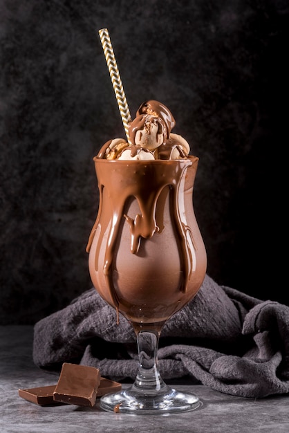 Vue de face du dessert au chocolat en verre avec de la paille