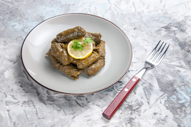 Vue de face du dolma feuille savoureuse à l'intérieur de la plaque sur une surface blanche