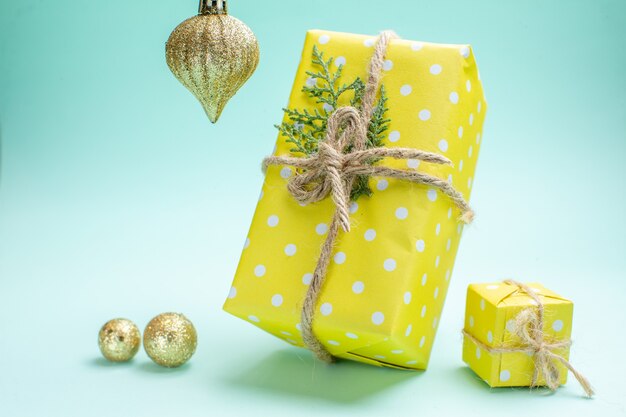 Vue de face du fond de Noël avec des coffrets cadeaux jaunes et des accessoires de décoration sur fond vert pastel