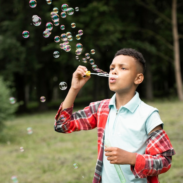 Vue de face du garçon faisant des bulles de savon