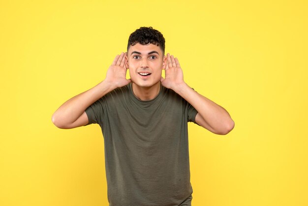 Vue de face du gars souriant tient sa main près de son oreille