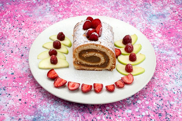 Vue de face du gâteau au chocolat à l'intérieur de la plaque blanche avec des fraises sur le bureau rose