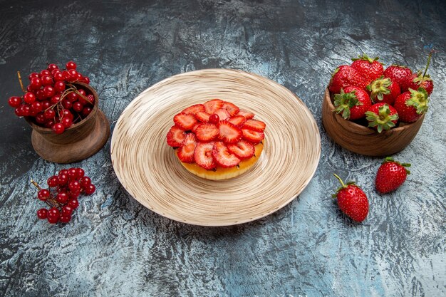 Vue de face du gâteau fruité avec des fraises fraîches sur une surface sombre