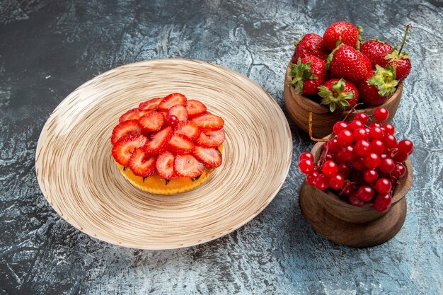 Vue de face du gâteau fruité avec des fraises fraîches sur une surface sombre