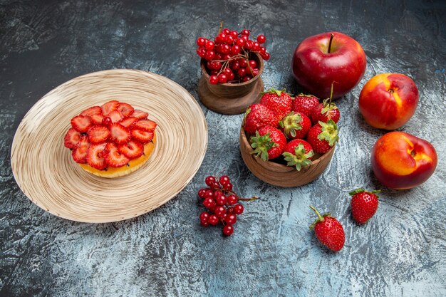 Vue de face du gâteau fruité avec des fraises fraîches sur une surface sombre