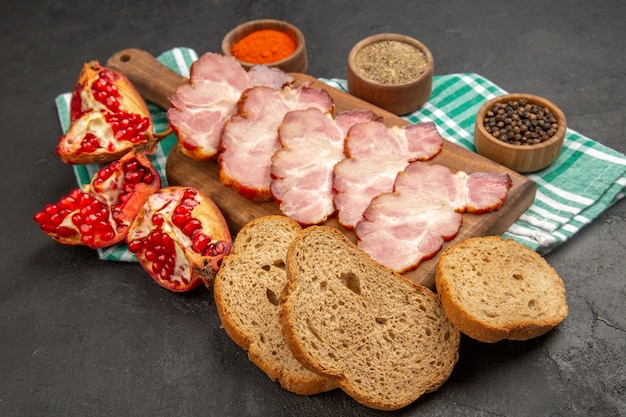 Vue de face du jambon frais tranché avec des assaisonnements sur de la viande de couleur photo crue de nourriture sombre