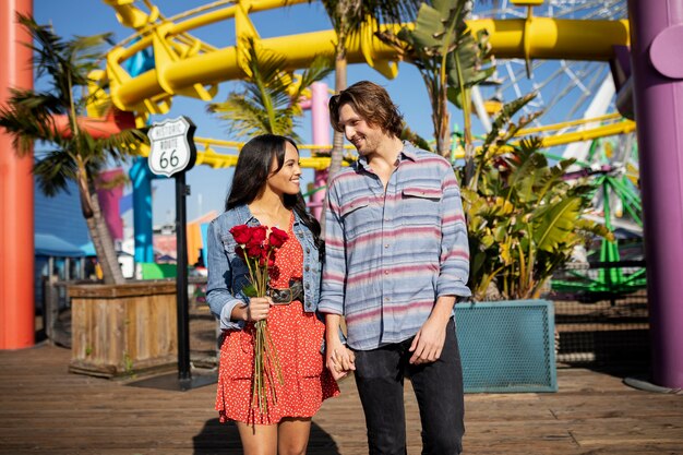 Vue de face du jeune couple au parc d'attractions ayant un rendez-vous