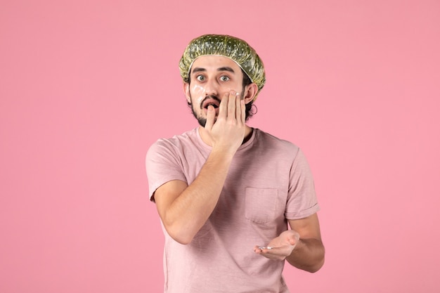 Photo gratuite vue de face du jeune homme appliquant un masque sur son visage sur un mur rose