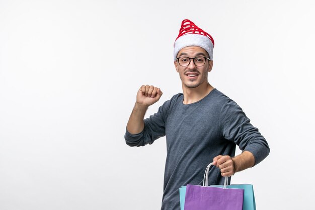 Vue de face du jeune homme après les achats de vacances sur mur blanc