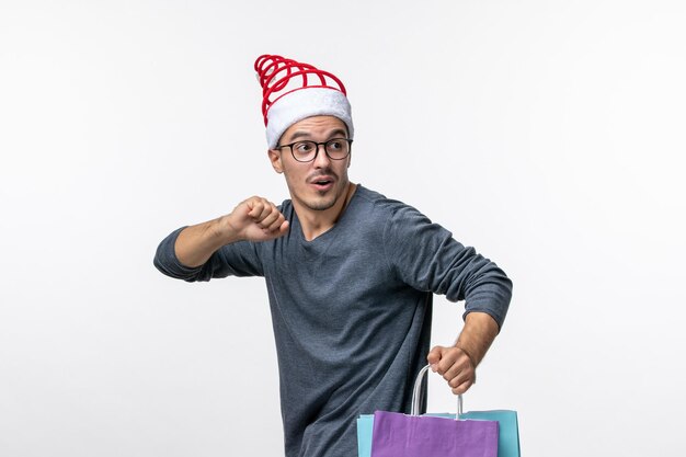 Vue de face du jeune homme après les achats de vacances sur mur blanc