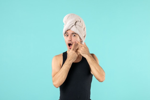 vue de face du jeune homme après la douche avec bouton sur son visage sur mur bleu