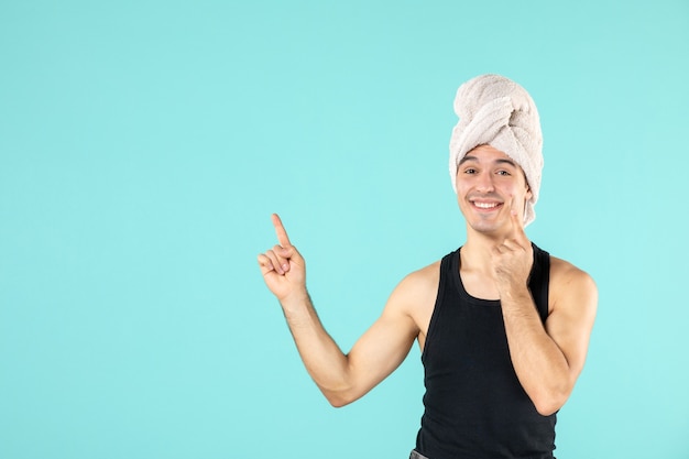 vue de face du jeune homme après la douche souriant sur le mur bleu