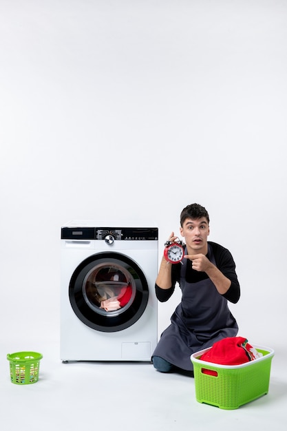 Photo gratuite vue de face du jeune homme attendant la fin du lavage des vêtements sur un mur blanc