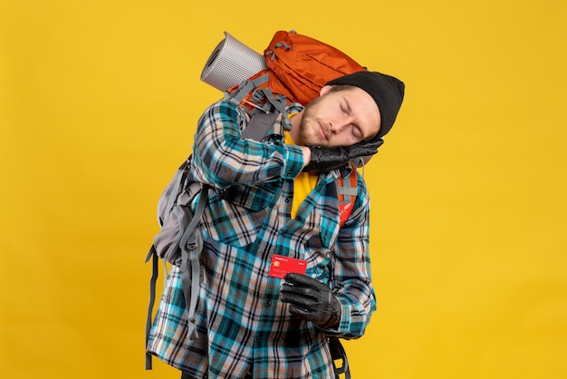 Vue de face du jeune homme barbu avec backpacker holding carte de crédit dormir