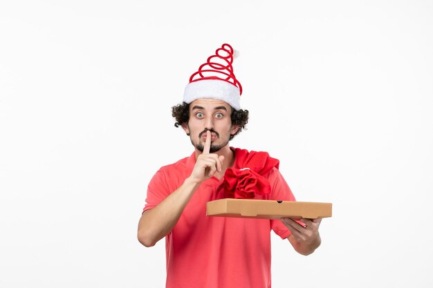 Vue de face du jeune homme avec une boîte de livraison de nourriture sur un mur blanc