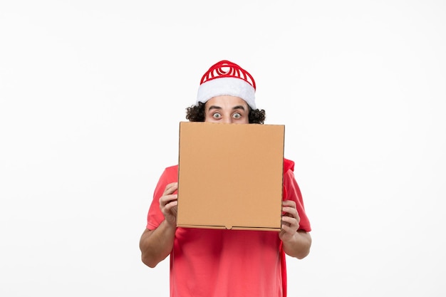 Vue de face du jeune homme avec une boîte de livraison de nourriture sur un mur blanc