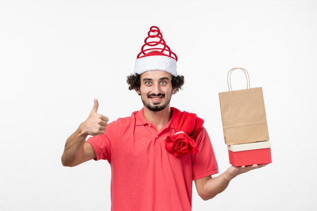 Vue De Face Du Jeune Homme Avec Des Cadeaux De Vacances Sur Mur Blanc