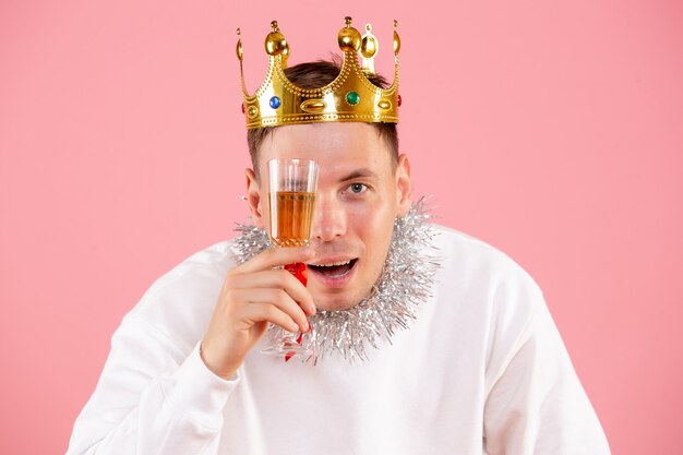 Vue de face du jeune homme célébrant Noël avec boisson sur un mur rose clair