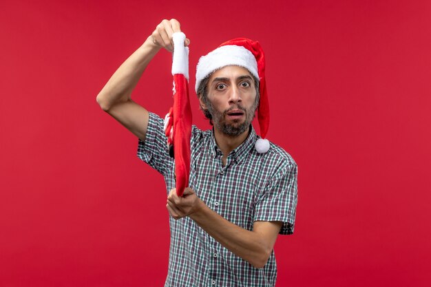 Vue de face du jeune homme avec chaussette de Noël sur le mur rouge