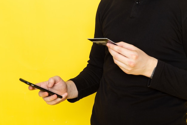 Photo gratuite vue de face du jeune homme en chemise noire à l'aide de téléphone