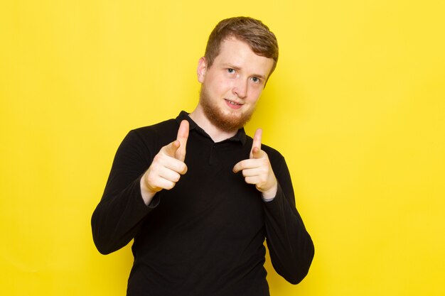 Vue de face du jeune homme en chemise noire posant avec bonne humeur