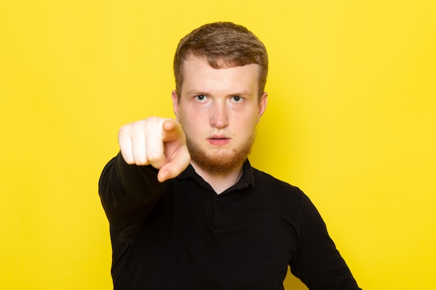 Vue de face du jeune homme en chemise noire posant et soulignant