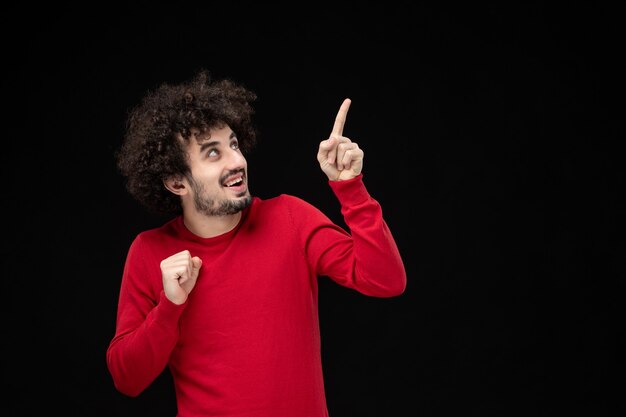 Vue de face du jeune homme en chemise rouge sur mur noir