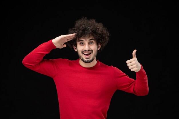 Vue de face du jeune homme en chemise rouge sur mur noir