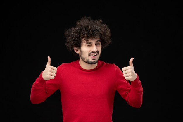 Vue de face du jeune homme en chemise rouge sur mur noir