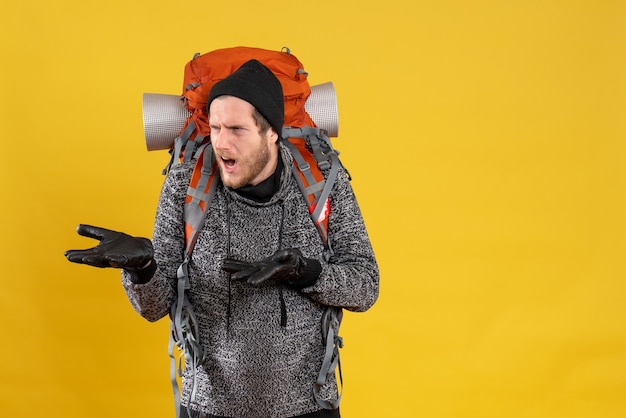 Vue de face du jeune homme confus avec des gants en cuir et sac à dos