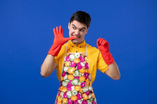 Vue De Face Du Jeune Homme Enlevant Ses Gants Sur Le Mur Bleu