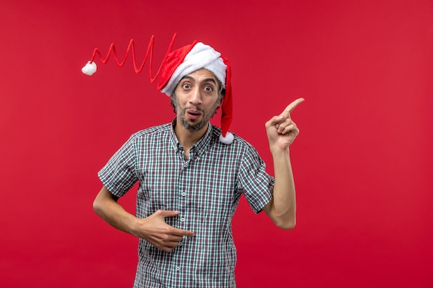 Vue de face du jeune homme avec une expression calme sur le mur rouge