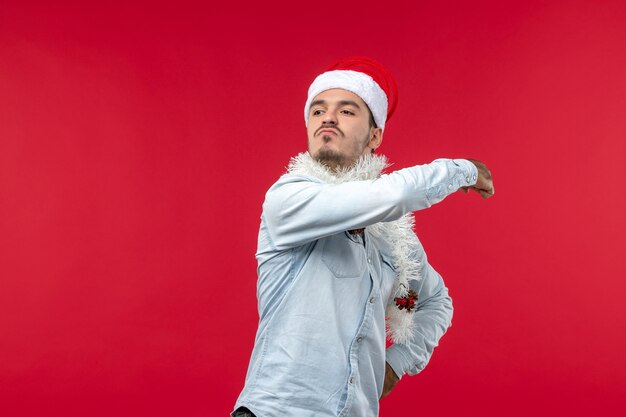 Vue de face du jeune homme avec une expression de colère sur le mur rouge