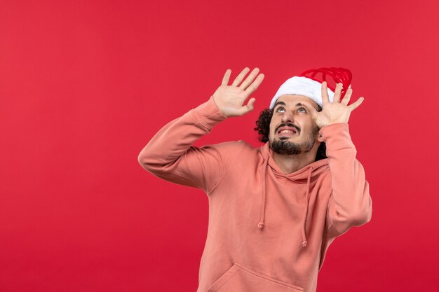 Vue de face du jeune homme avec une expression effrayée sur le mur rouge