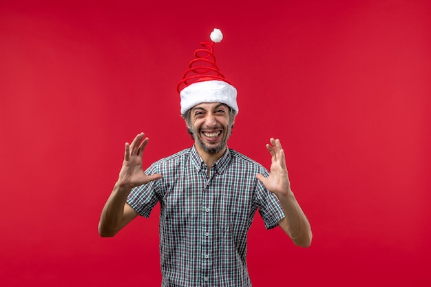 Vue de face du jeune homme avec une expression excitée sur le mur rouge