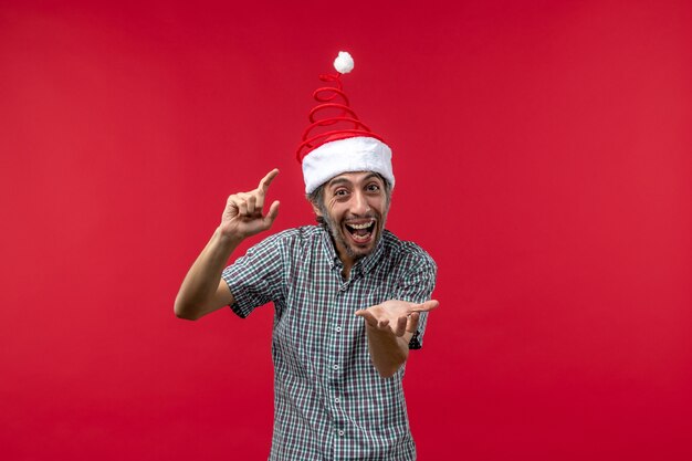 Vue de face du jeune homme avec une expression excitée sur le mur rouge