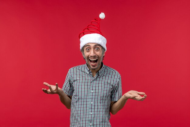 Vue de face du jeune homme avec une expression excitée sur le mur rouge