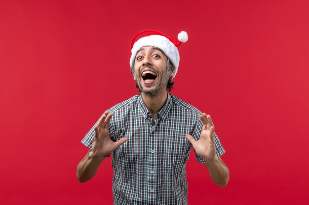 Vue de face du jeune homme avec une expression excitée sur le mur rouge