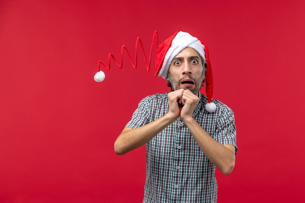 Vue de face du jeune homme avec une expression nerveuse sur le mur rouge